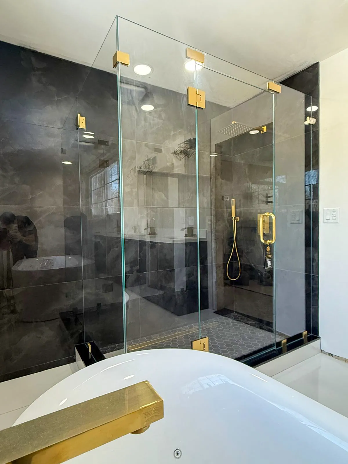 Frameless shower enclosure with gold hardware