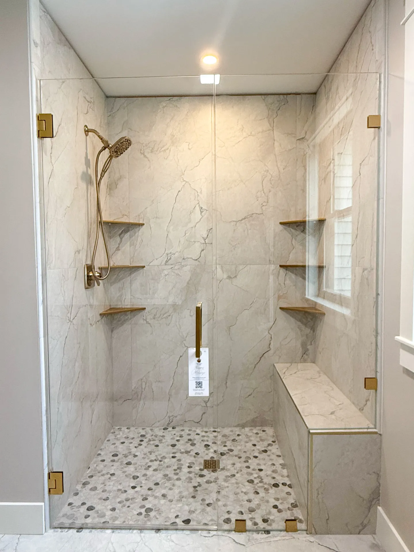 Marble shower with gold shelving and glass panel