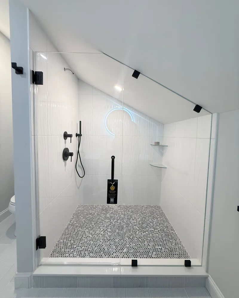 Frameless panel cut to a sloped attic ceiling shower with matte black hardware