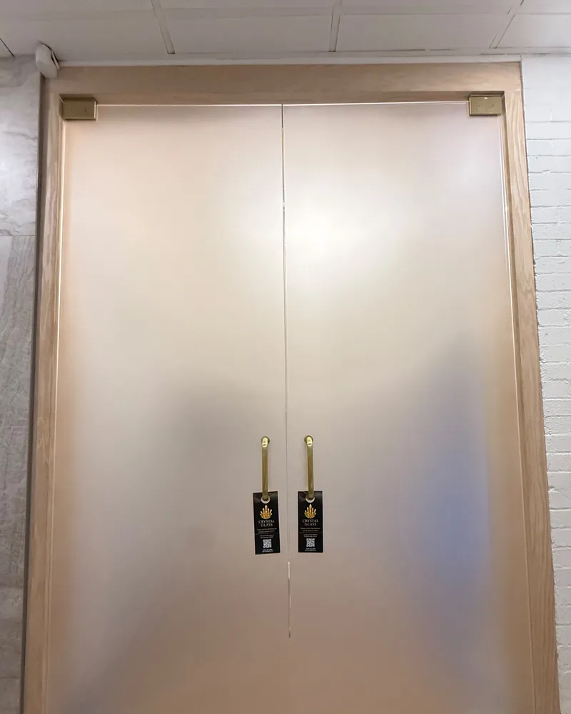 Pair of frosted glass doors with gold handles closing a bathroom opening
