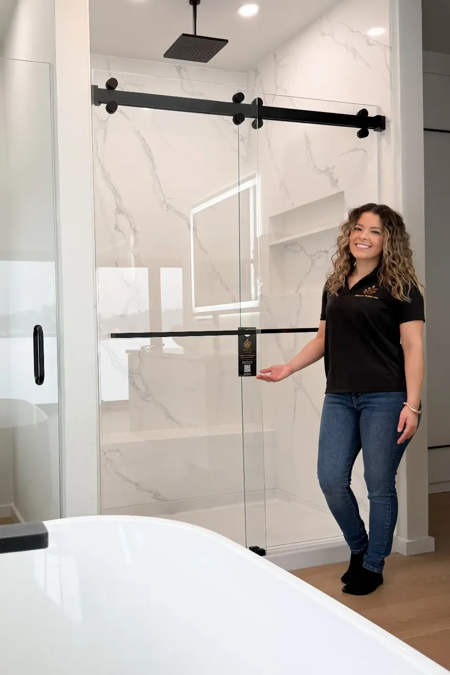 Midia from Crystal Glass in a company polo, standing beside a finished glass shower enclosure